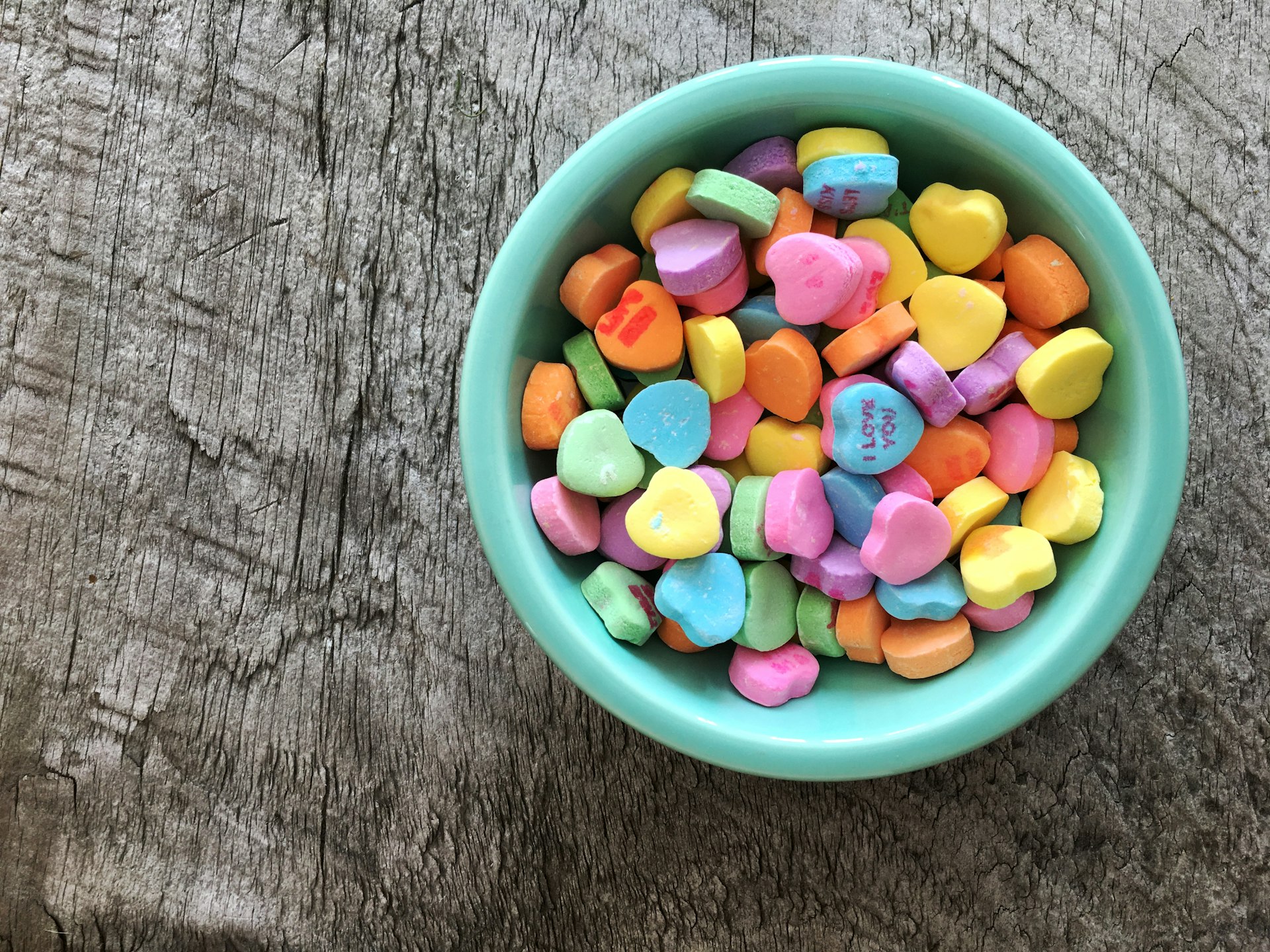 assorted-color heart shape candies on teal bowl